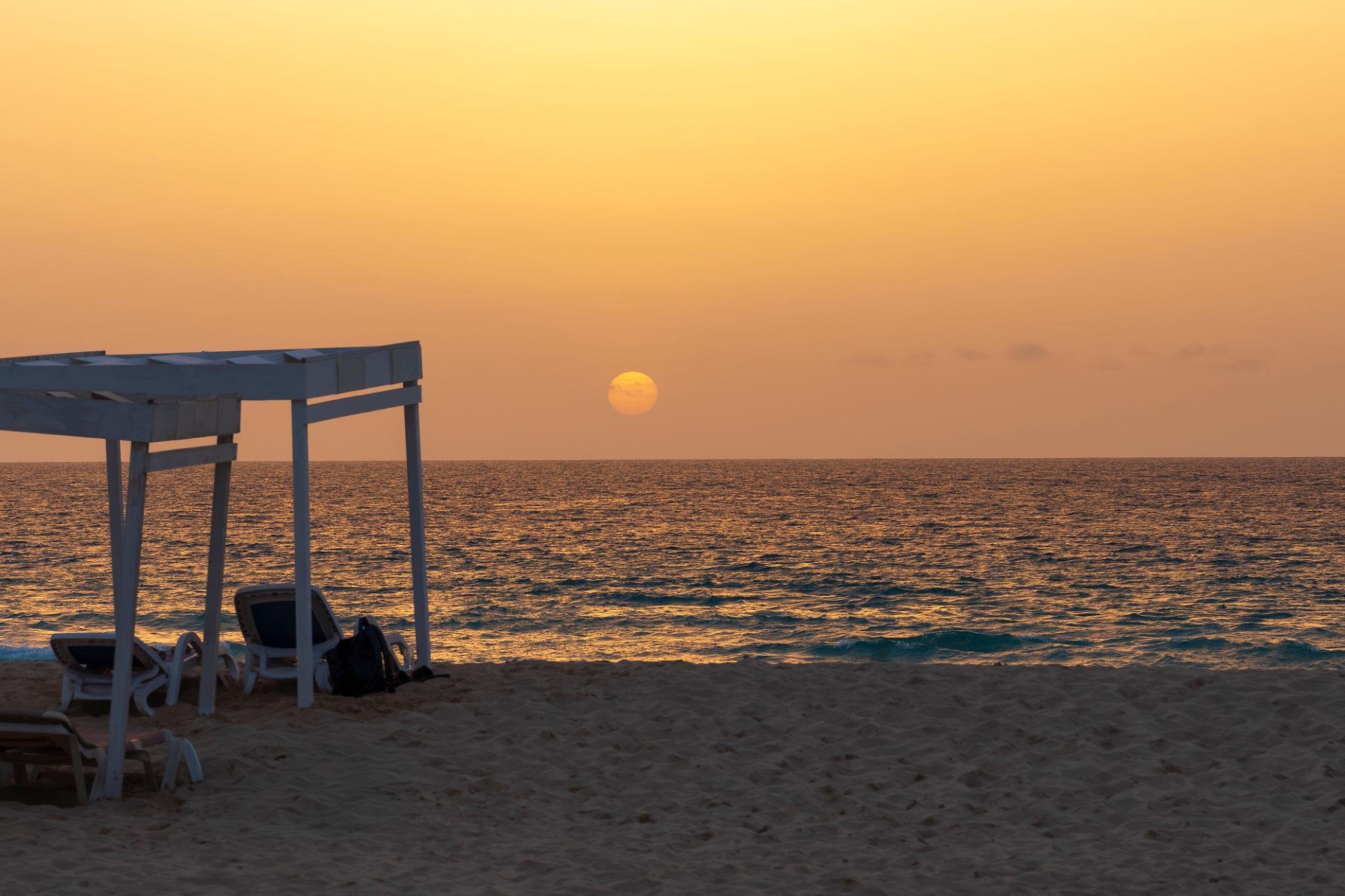 Sun loungers under a cabana at golden-hour sunset on a Cape Verde beach