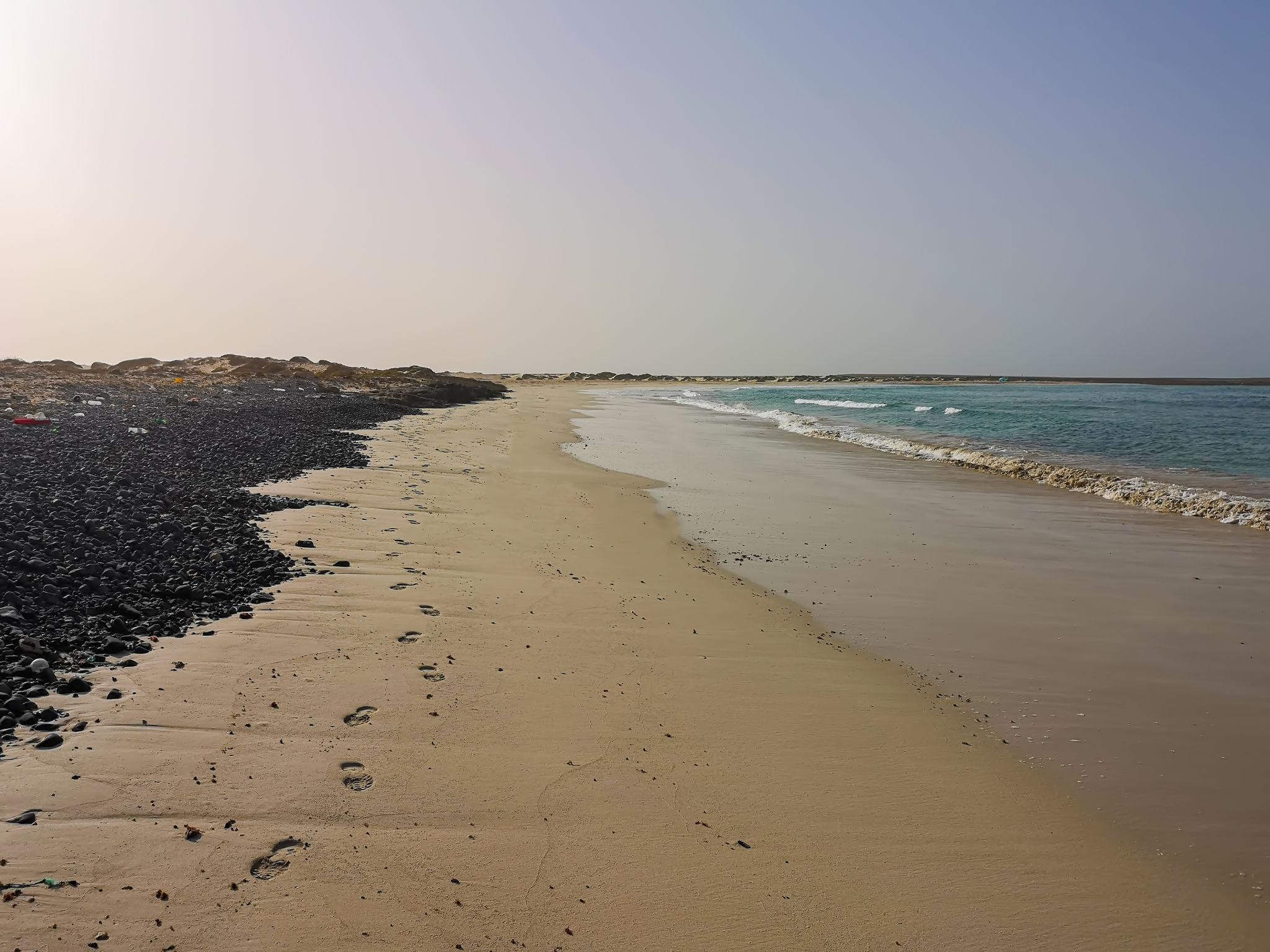 Quiet Cape Verde beach with footprints beside clear Atlantic water